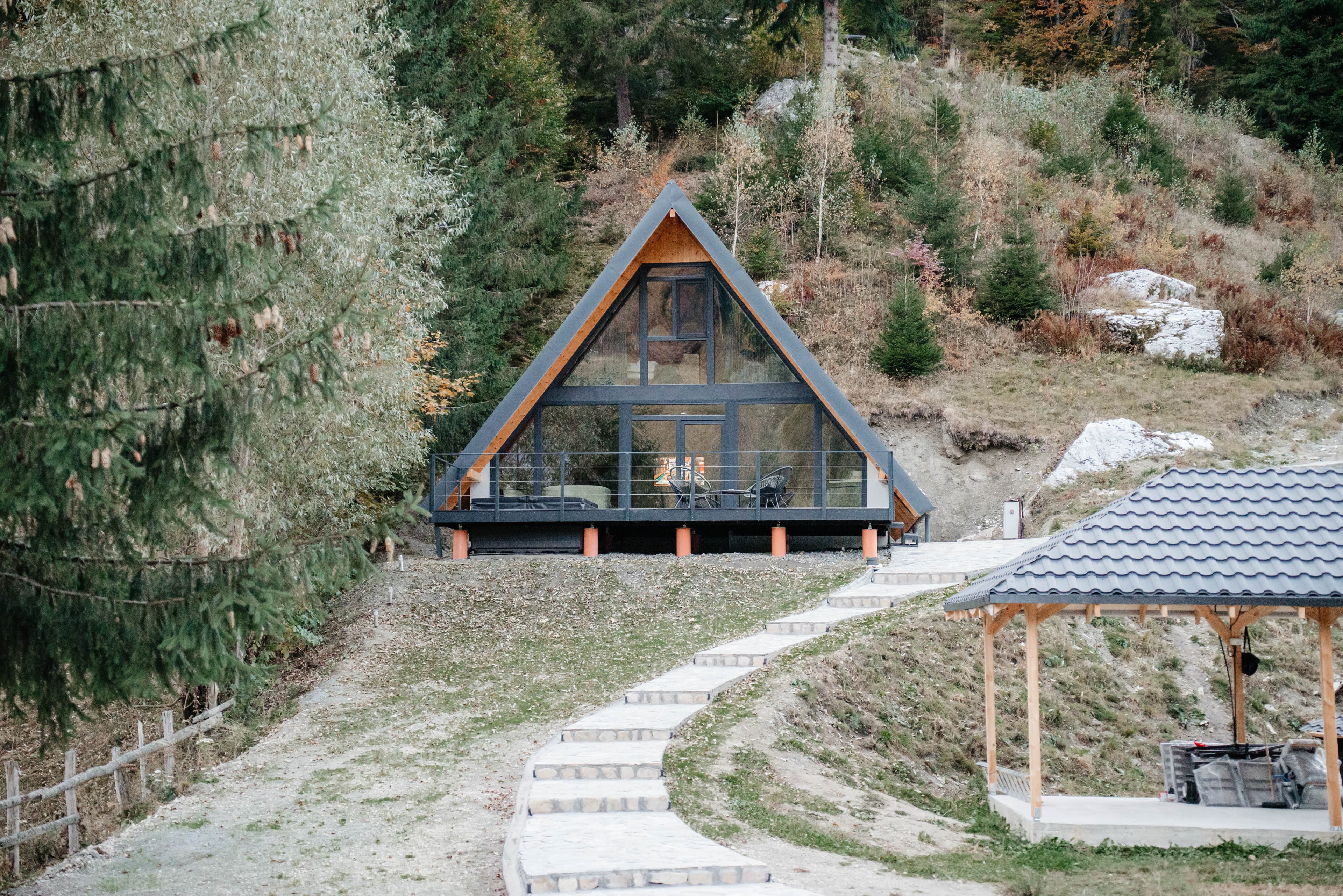 Căsuță în formă de A cu ferestre luminate, printre copaci înalți